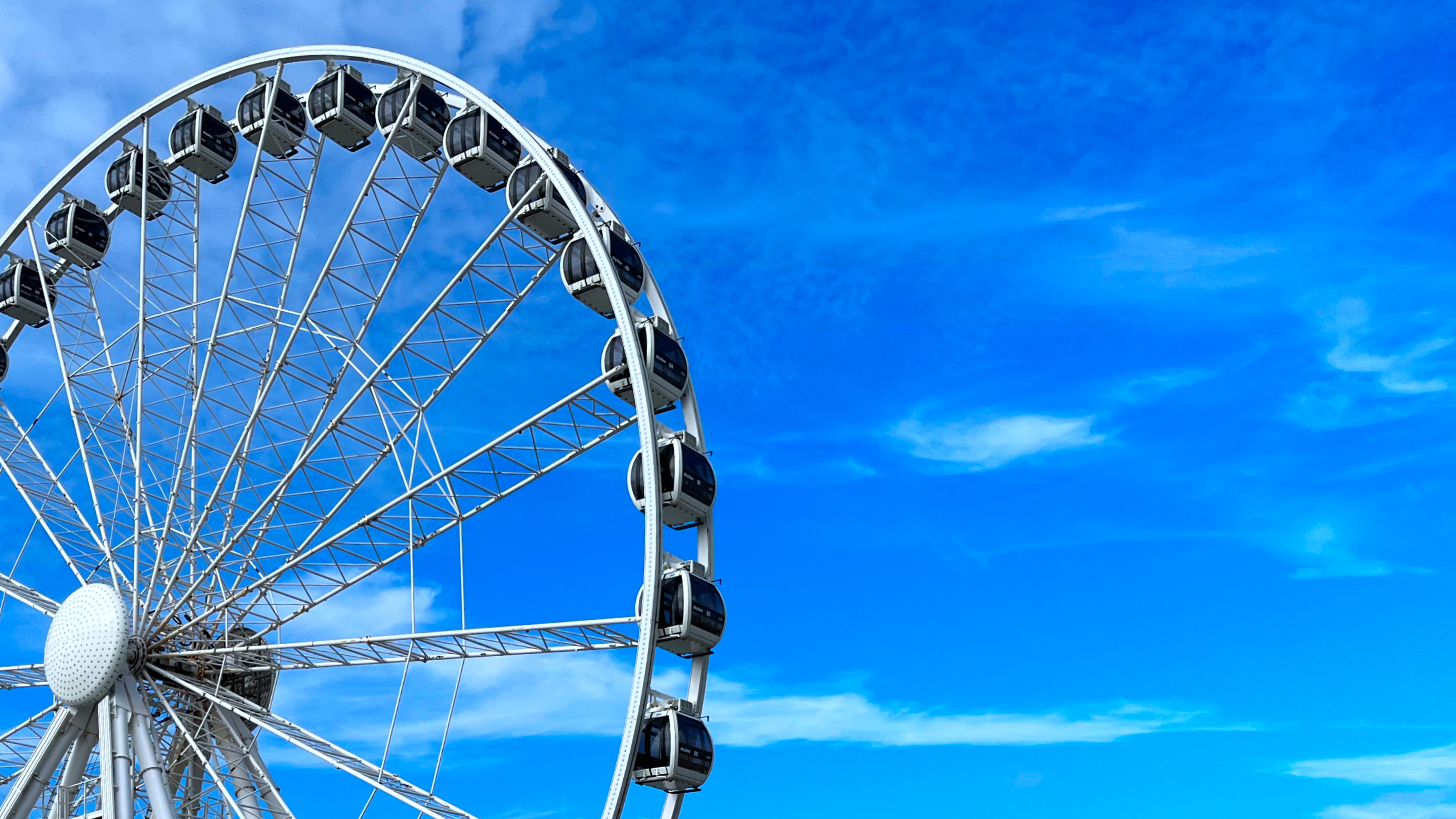 Large Ferris wheel against a bright blue sky at Scheveningen Pier, The Hague, with no visible people.